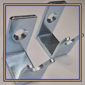 May include: Two L-shaped metal brackets with a silver finish. Each bracket has a hole for mounting and a curved hook. The brackets are designed for support or hanging applications.