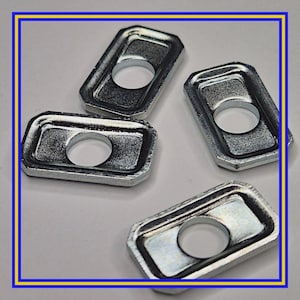 Könnte beinhalten: Vier rechteckige Metallscheiben mit einem zentralen kreisförmigen Loch. Die Scheiben haben eine silberne Oberfläche und sind auf einer weißen Oberfläche angeordnet. Das Bild ist mit einem blauen und gelben Rahmen versehen.