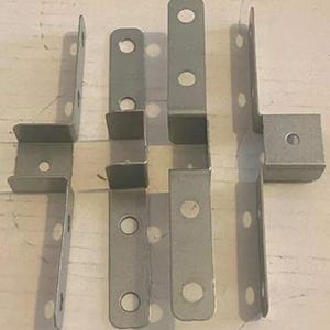 May include: Set of ten silver metal corner brackets with four holes each. The brackets are L-shaped and have a smooth finish.