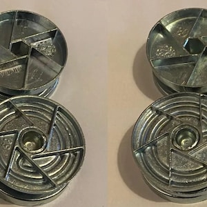 May include: Six silver metal circular objects with a star-shaped design and a center hole. The objects are stacked in pairs.