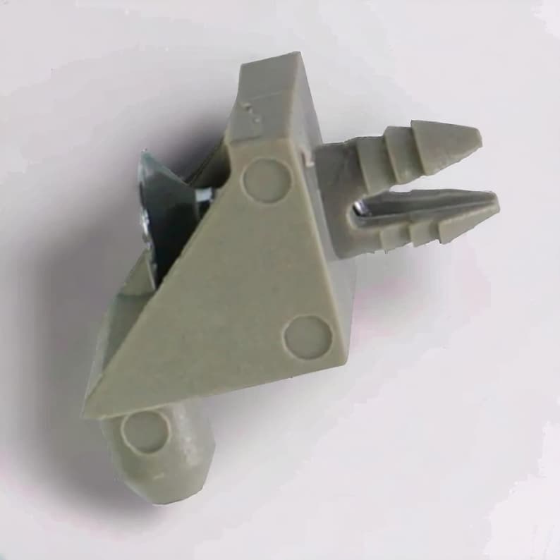 Puede incluir: Un cierre de pl&aacute;stico gris con una base triangular y un extremo puntiagudo. El cierre tiene tres agujeros circulares en la base y una serie de crestas en el extremo puntiagudo.