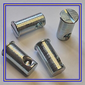 Pode incluir: Quatro rebites de metal prateado com cabeça ranhurada e interior roscado. Cada rebite tem um corpo cilíndrico com um furo. Os rebites estão dispostos sobre uma superfície branca.