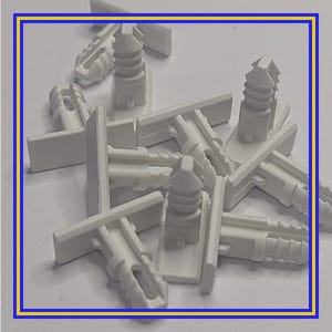 Pode incluir: Uma pilha de rebites de pressão, fixadores ou clipes de plástico branco. Cada clipe tem uma base retangular e um poste cilíndrico ranhurado com uma cabeça hexagonal. Os clipes são projetados para fixação segura.