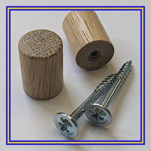 Może przedstawiać: Dwa drewniane kołki i dwie srebrne śruby z płaskimi łbami są wyświetlane na białym tle. Kołki są cylindryczne, w jasnobrązowym kolorze i z widocznym usłojeniem drewna. Śruby mają krzyżowy wklęs.