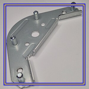 May include: A silver metal right-angled bracket with several cylindrical posts and circular holes. The bracket has a curved section and a flat, rectangular extension. This component is likely for furniture or construction purposes.