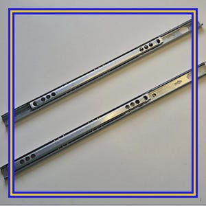 Puede incluir: Dos guías de cajón de metal plateado, en ángulo diagonal. Cada guía tiene múltiples agujeros pequeños y una serie de aberturas circulares más grandes. Diseñadas para un movimiento suave del cajón, probablemente para muebles.