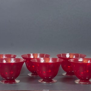 May include: Six red glass dessert bowls with a clear glass base. The bowls are arranged in two rows of three.