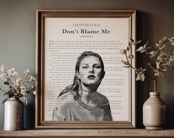 Puede incluir: Una impresión enmarcada con el texto "Don't Blame Me" y un retrato de una mujer. La obra de arte se exhibe en una repisa de madera, con jarrones de flores a ambos lados. La impresión tiene una estética vintage.