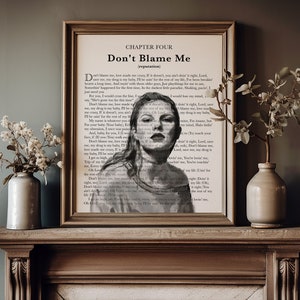 May include: A framed print featuring the text "Don't Blame Me" and a portrait of a woman. The artwork is displayed on a wooden mantelpiece, with vases of flowers on either side. The print has a vintage aesthetic.