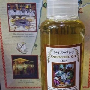 May include: A clear glass bottle of Holy Land Legacy Anointing Oil, labeled "Nard." The label features an image of people and text. The bottle contains 100 ml of oil and has a white cap. The background includes a map and images.