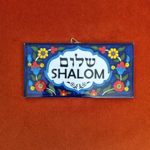 May include: A blue and white ceramic sign with a floral design and the word "SHALOM" in Hebrew and English.