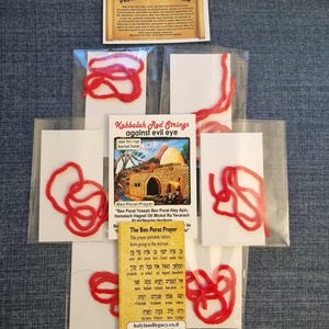May include: Five red string bracelets packaged individually in clear plastic bags. Each bag includes a small card with the text "Kabbalah Red Strings against evil eye" and a picture of Rachel's Tomb. The card also includes the text "Ben Porat Prayer" and a Hebrew prayer.