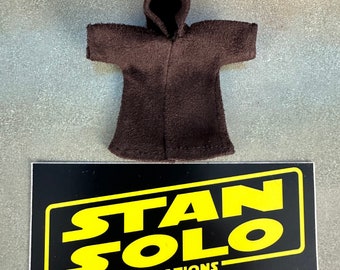 May include: A brown hooded robe with long sleeves. The robe is laying flat on a gray surface. The text "STAN SOLO CREATIONS" is printed on a black background.
