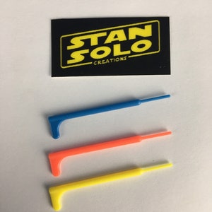 May include: Three lightsaber blades in blue, orange, and yellow. The blades are made of plastic and are about 6 inches long. The blades are for use with a lightsaber toy. The image also includes a black card with the text "STAN SOLO CREATIONS".