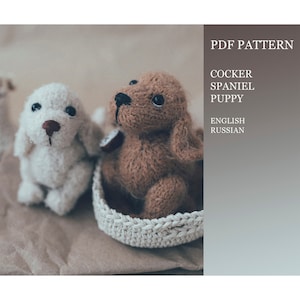 Puede incluir: Patrón PDF para tejer un cachorro Cocker Spaniel. El patrón incluye instrucciones en inglés y ruso. La imagen muestra dos cachorros tejidos, uno marrón y otro blanco, sentados en una cesta tejida.
