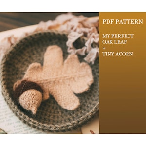 May include: A knitted oak leaf and acorn set in a woven basket. The leaf is beige, and the acorn has a brown cap. The basket is a muted green color. Text on the right side reads "PDF PATTERN, MY PERFECT OAK LEAF + TINY ACORN."