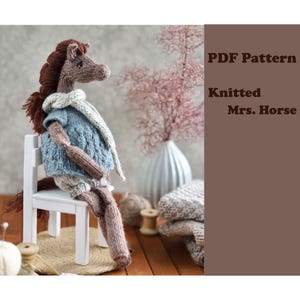 Puede incluir: Una muñeca de punto Mrs. Horse con melena y cola marrones, que lleva un suéter azul y una bufanda blanca, sentada en una pequeña silla blanca. La muñeca está hecha de hilo y tiene un diseño caprichoso. El texto "PDF Pattern Knitted Mrs. Horse" es visible.