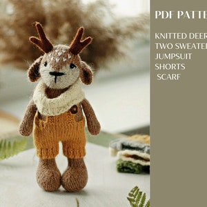 May include: Knitted deer amigurumi toy wearing a brown and white sweater, brown shorts, and a white scarf. The toy is sitting on a white surface with a green plant in the background. The text "PDF PATTERN" is in the upper right corner of the image. The text "KNITTED DEER TWO SWEATERS JUMPSUIT SHORTS SCARF" is below the "PDF PATTERN" text.