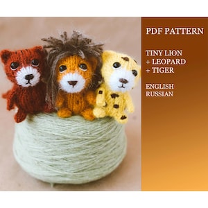 May include: Three knitted animal toys: a red tiger, an orange lion with a brown mane, and a yellow leopard. The toys are sitting on a ball of yarn. The image includes the text "PDF PATTERN TINY LION + LEOPARD + TIGER ENGLISH RUSSIAN".