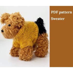 Könnte beinhalten: Ein PDF-Muster für einen gestrickten Hundepullover. Das Muster ist für einen gelben Pullover mit schwarzem Kragen und einem schwarzen Patch auf dem Rücken.