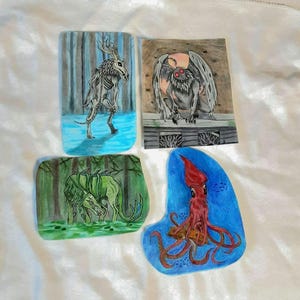 May include: Four hand-painted illustrations of mythical creatures on a white background. The first illustration shows a skeletal deer-like creature in a blue forest. The second illustration shows a moth-like creature with red eyes in a brown cave. The third illustration shows a green creature with a long tail in a green forest. The fourth illustration shows a red squid-like creature in a blue ocean.
