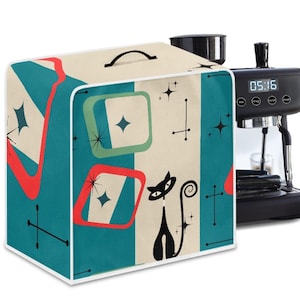May include: A retro-style appliance cover with a teal, cream, and red geometric pattern. The cover features a black cat silhouette and starburst designs. A black espresso machine is partially visible on the right.