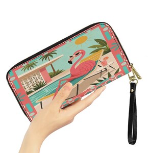 May include: A zippered wallet featuring a flamingo wearing sunglasses, lounging on a beach chair. The wallet has a black zipper and wrist strap, with a colorful illustration of a sunny day at a pool.