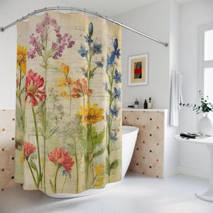 May include: A floral shower curtain featuring a vintage botanical design. The curtain showcases colorful flowers in shades of red, yellow, pink, and blue against a cream-colored background with script-like text. The curtain is hanging in a bathroom.