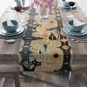 May include: A beige table runner with a geometric pattern featuring black cats, blue and orange accents, and a white grid background.