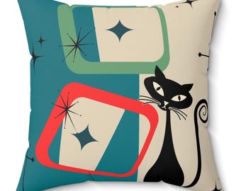 May include: A teal blue, red, and green geometric pattern pillow with a black cat silhouette. The cat has a white face and a curled tail.