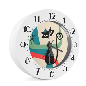 May include: White round clock with a retro design featuring a black cat silhouette and a mid-century modern style background in teal, red, and beige. The clock face has black numbers and hands.
