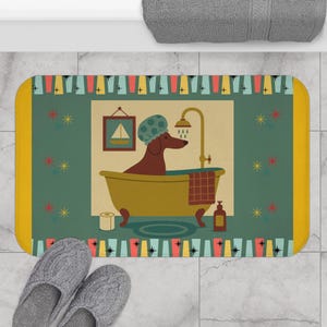 May include: A rectangular bath mat with a whimsical illustration of a dachshund taking a bath. The mat features a green background with a yellow border and a repeating pattern. The dog is brown and wearing a shower cap.