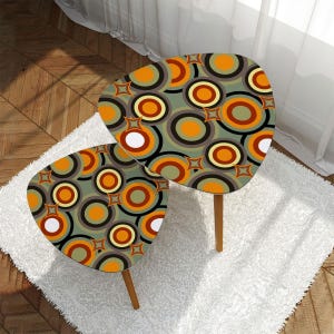 May include: Two nesting tables with a retro, geometric pattern of orange, yellow, white, and gray circles on a green background. The tables are made of wood and have a unique, asymmetrical shape.