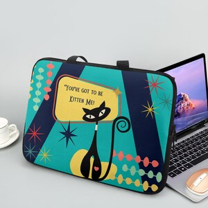 May include: A black laptop sleeve with a retro cat design. The teal background features navy blue stripes, starbursts, and the text "You've got to be Kitten Me!". A black cat with a heart is in the center.