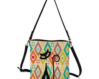 May include: A cream-colored crossbody bag with a geometric pattern of diamonds in orange, teal, purple, and pink. A black cat illustration is on the front. The bag has a black strap and gold-colored hardware.