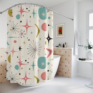 Può includere: Una tenda da doccia con sfondo bianco sporco e un motivo ripetuto di stelle, boomerang e forme circolari in rosa, verde acqua, nero e verde oliva. La tenda è appesa a un'asta metallica curva in un ambiente bagno.