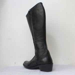 May include: Black leather knee-high boots with a zipper up the back and a low heel.