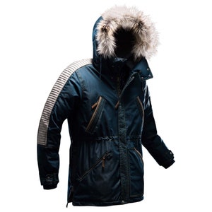 Puede incluir: Una chaqueta de invierno azul con capucha y un borde de piel sintética alrededor de la capucha. La chaqueta tiene una cremallera y varios bolsillos. La chaqueta tiene una franja blanca en la manga.