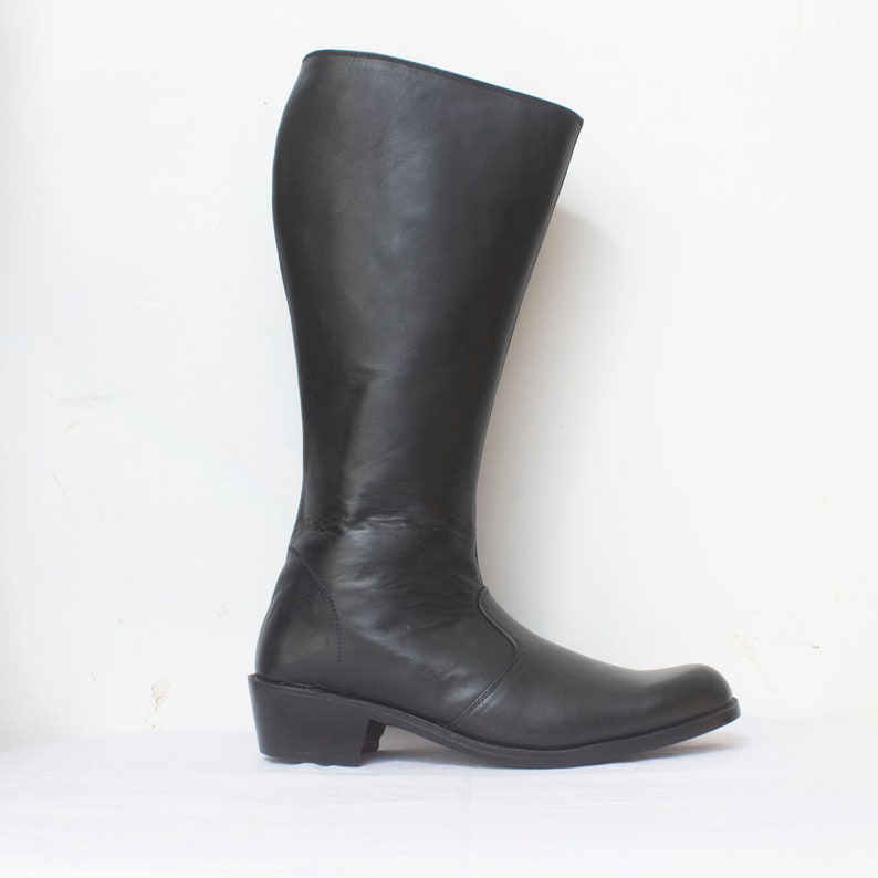 May include: A pair of black leather knee-high boots with a low heel.