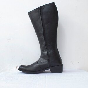 May include: Black leather knee-high boots with a zipper up the back and a low heel.
