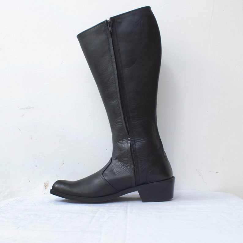 May include: Black leather knee-high boots with a zipper up the back and a low heel.