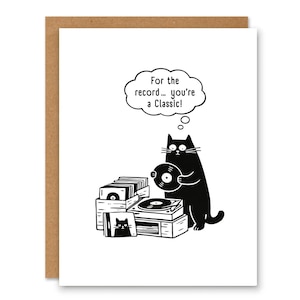 May include: Greeting card with a black cat cartoon holding a vinyl record. The cat is standing next to a record player and stacks of vinyl records. Text in a thought bubble reads, "For the record... you're a Classic!"
