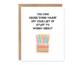 Puede incluir: Tarjeta de felicitación de cumpleaños con borde marrón. La tarjeta presenta el texto "YOU CAN CROSS 'DYING YOUNG' OFF YOUR LIST OF STUFF TO WORRY ABOUT" sobre una colorida tarta con velas encendidas.