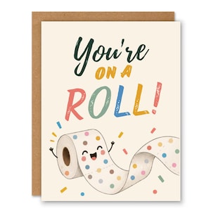 May include: A greetings card with a cream background featuring the text "You're ON A ROLL!" in dark green, orange, pink, light green, blue, and yellow. Below the text is a cartoon toilet paper roll with a happy face and colourful polka dots.