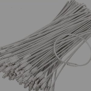 Puede incluir: Una gran colección de cables metálicos plateados para llaveros. Cada cable flexible cuenta con un conector de barril roscado en los extremos, lo que permite formar un bucle seguro. Los cables están dispuestos en un haz denso y superpuesto.