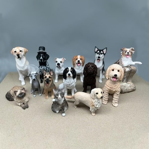 May include: A selection of dog and cat ornaments in different breeds and poses. The figurines are painted with realistic details and colours, including a Labrador, a Husky, and a Golden Doodle. The collection includes a variety of dog breeds and two cat ornaments.