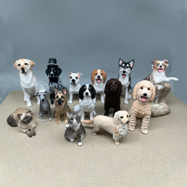 May include: A selection of dog and cat ornaments in different breeds and poses. The figurines are painted with realistic details and colours, including a Labrador, a Husky, and a Golden Doodle. The collection includes a variety of dog breeds and two cat ornaments.