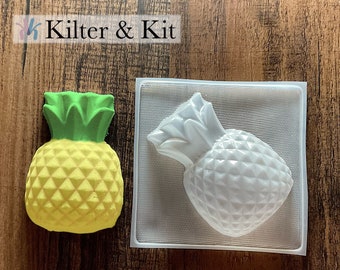 May include: A white plastic mold for making pineapple-shaped crafts. The mold is shown next to a yellow and green pineapple-shaped craft.