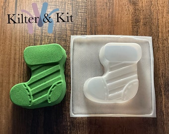 May include: A green Christmas stocking bath bomb with white stripes and a clear plastic mold of the same stocking.