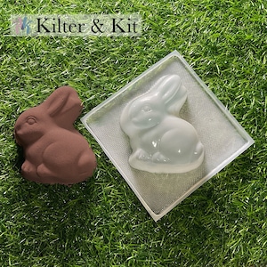 May include: A brown bunny-shaped object and a white bunny-shaped object in a clear plastic mold, both on a green surface. The text "Kilter & Kit" is at the top of the image.